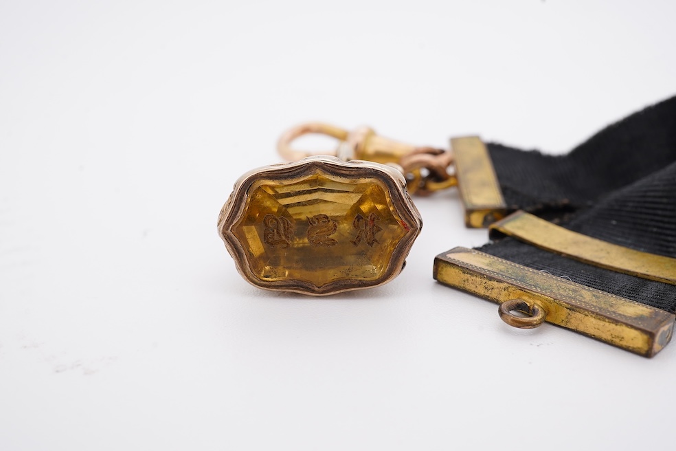 A late Victorian yellow metal overlaid and citrine set watch key fob, depicting two horses and two rams?, 30mm on a black sash suspension, together with a modern pair of 9ct gold and cultured pearl set leaf ear studs. Co